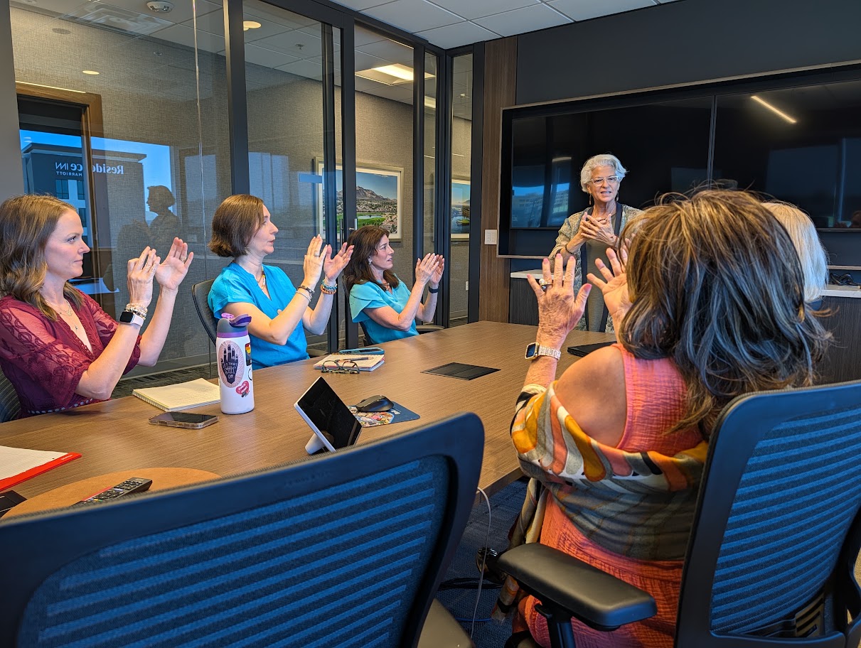 Angel Marie leading a corporate team through an energy calibration exercise in a conference room